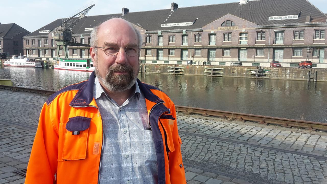 Ein Mann mit Bart und Brille steht am Westhafen in Berlin Ein Mann mit Bart und Brille steht am Westhafen in Berlin