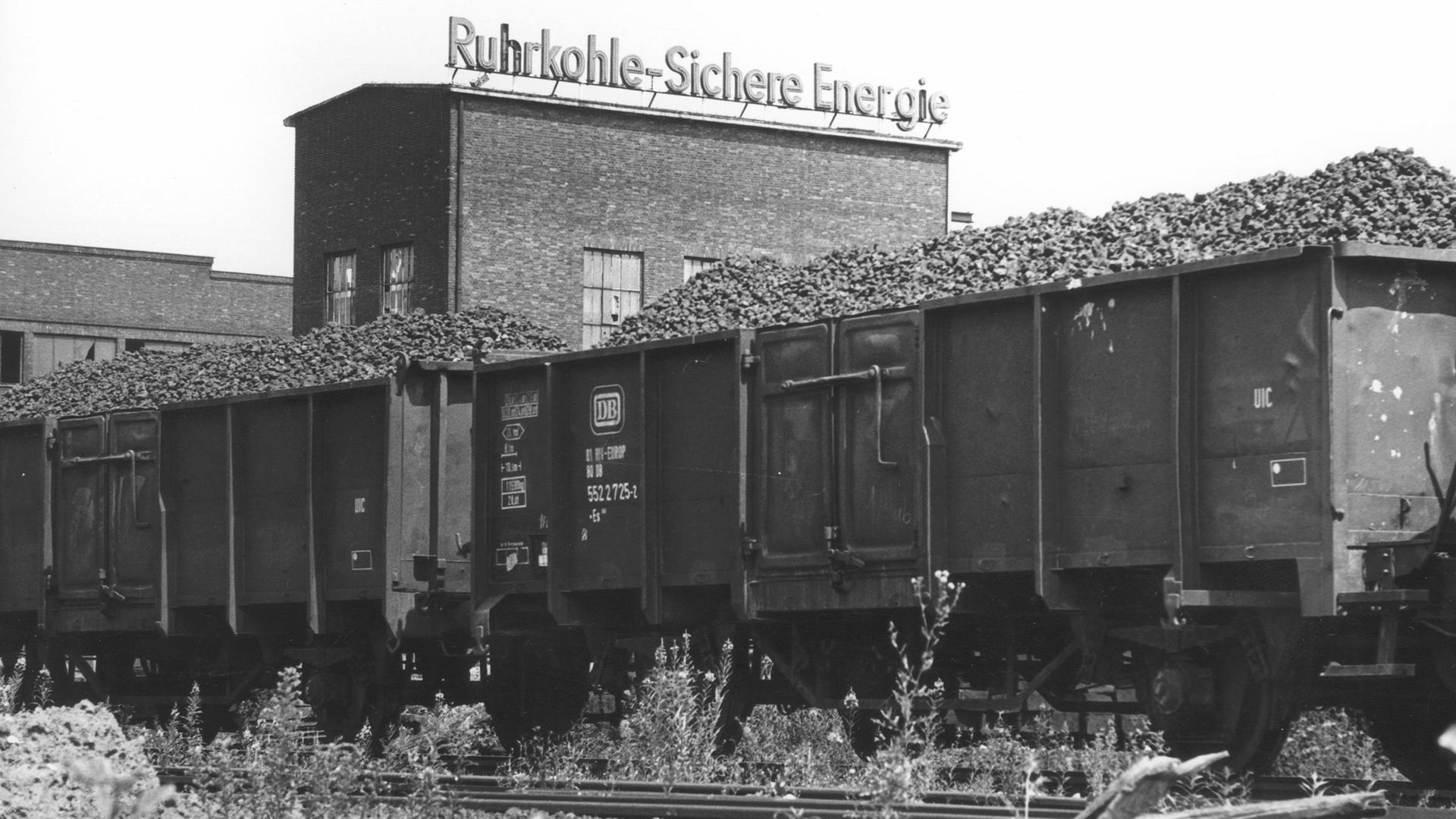 Kohlewagons vor einer Fabrik mit dem Werbeslogan: "Ruhrkohle, Sichere Energie". Bonn, 1979.