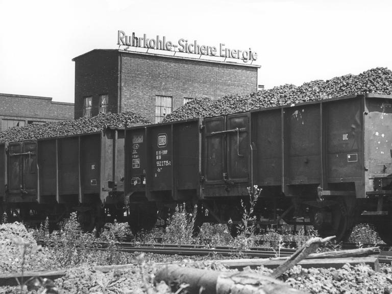 Kohlewagons vor einer Fabrik mit dem Werbeslogan: "Ruhrkohle, Sichere Energie". Bonn, 1979.