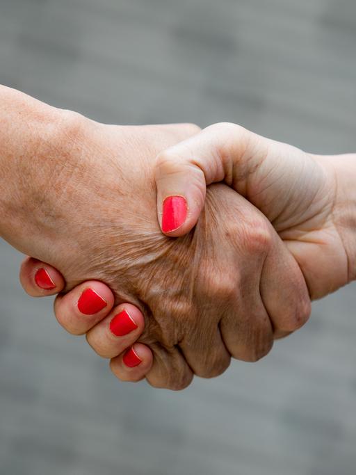 Zwei Menschen geben sich die Hand. 