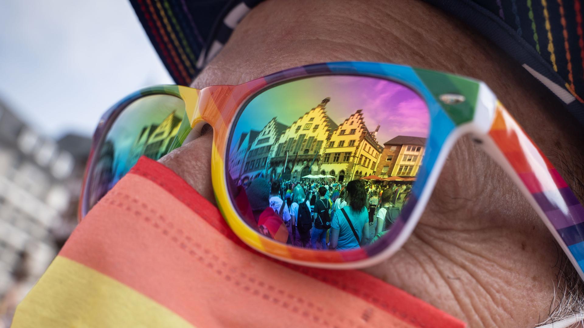In einer Sonnenbrille in Regenbogenfarben spiegelt sich beim  Christopher Street Day Frankfurt 2021 der Römer, das historische Rathaus der Stadt