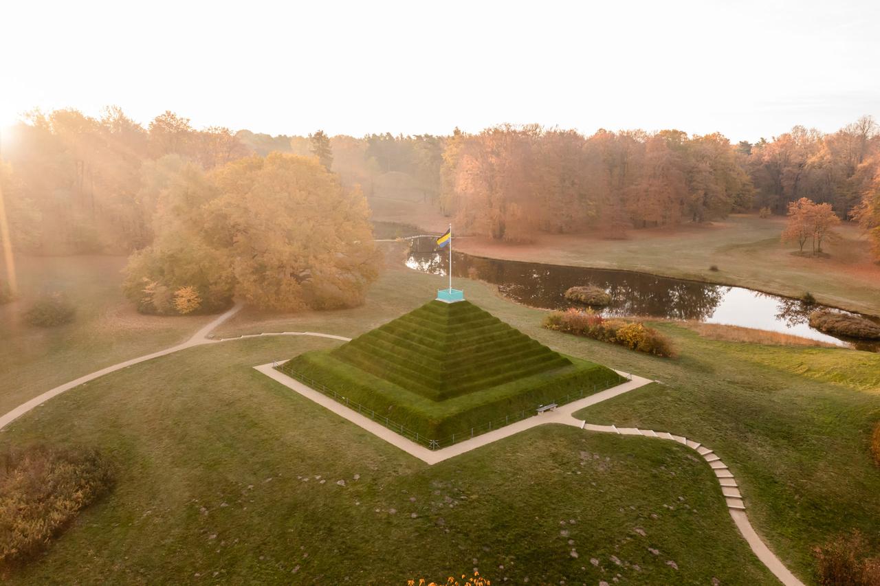 Blick von oben auf eine begrünte Steinpyramide in einem großen Park Blick von oben auf eine begrünte Steinpyramide in einem großen Park