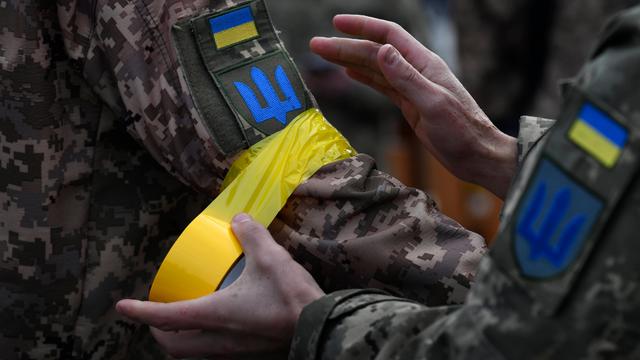 Ein ukrainischer Soldat macht einem Kameraden gelbes Klebeband an den Arm als Zeichen der Zugehörigkeit zu den regulären Streitkräften.