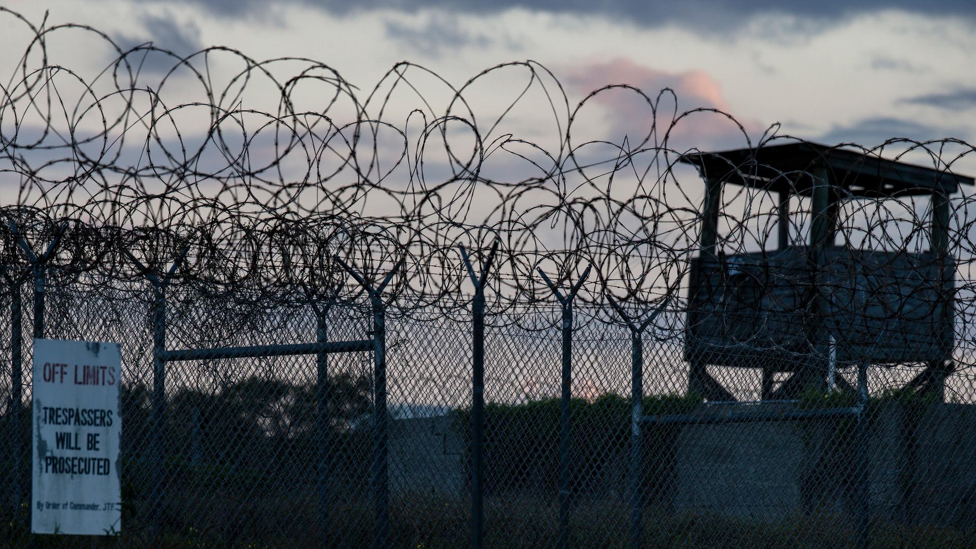 Zäune und Wachturm des US-Gefangenenlagers Guantánamo in der Dämmerung.