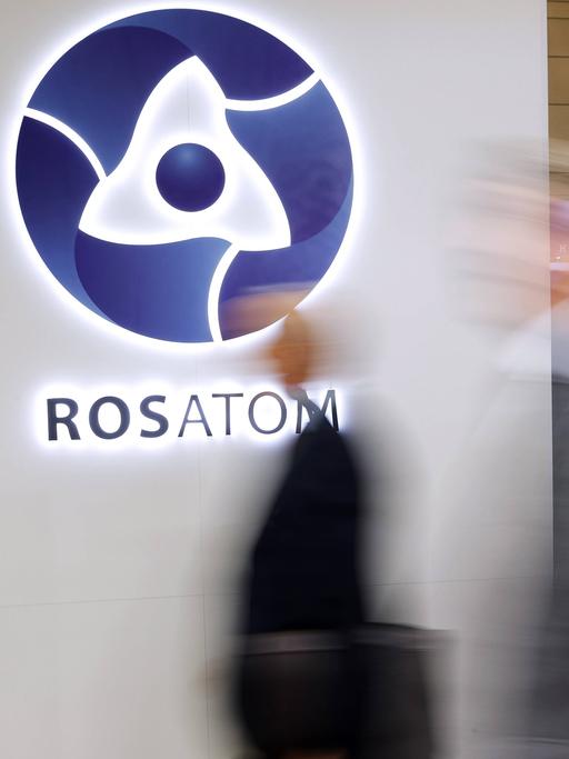Ein Messestand des Konzerns Rosatom zeigt das Logo des Unternehmens. Im Vordergrund sind unscharf Passanten zu erkennen.