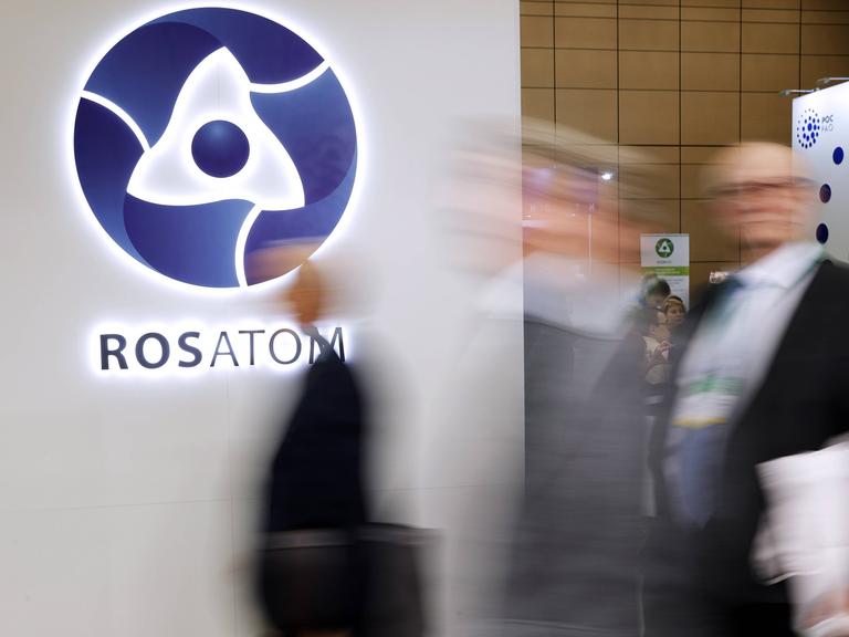 Ein Messestand des Konzerns Rosatom zeigt das Logo des Unternehmens. Im Vordergrund sind unscharf Passanten zu erkennen.