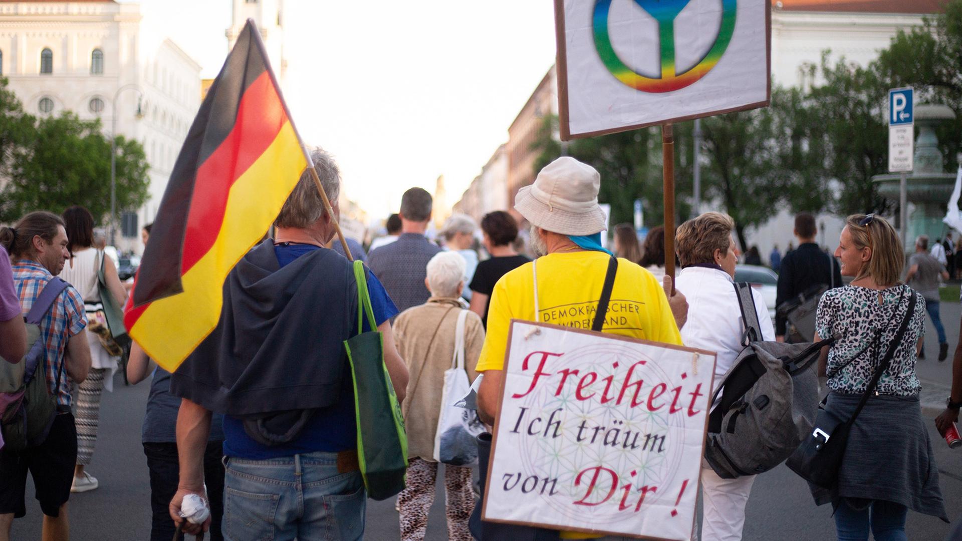Menschen auf einer Demonstration. Ein Mann mit einem Plakat auf dem Rücken: Freiheit ich träum von Dir! Menschen auf einer Demonstration. Ein Mann mit einem Plakat auf dem Rücken: Freiheit ich träum von Dir!