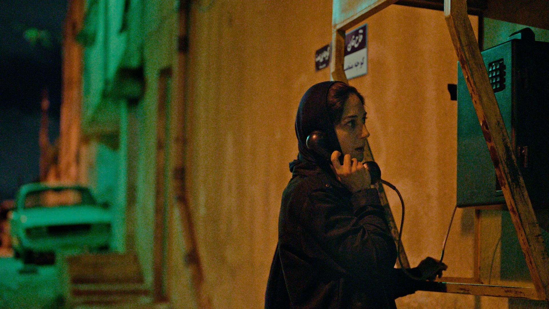 Filmstill aus dem Film "Holy Spider": Eine Frau mit Kopftuch telefoniert an einer Telefonzelle. Filmstill aus dem Film "Holy Spider": Eine Frau mit Kopftuch telefoniert an einer Telefonzelle.