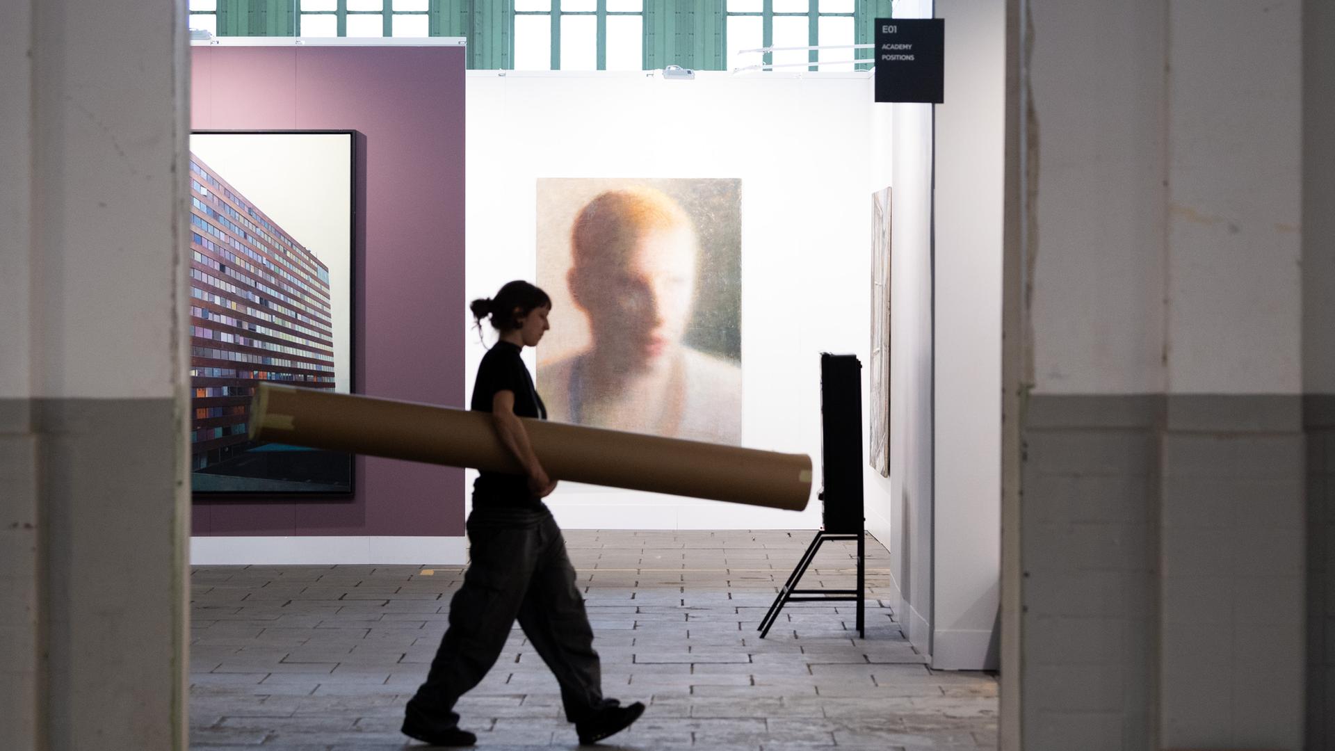 Eine Frau geht während der Pressekonferenz zur Kunstmesse "Positions Berlin Art Fair im Hangar 4 des Flughafens Tempelhof an Bildern vorbei. Die Messe fand vom 12. bis 15. 09.2019 statt. 