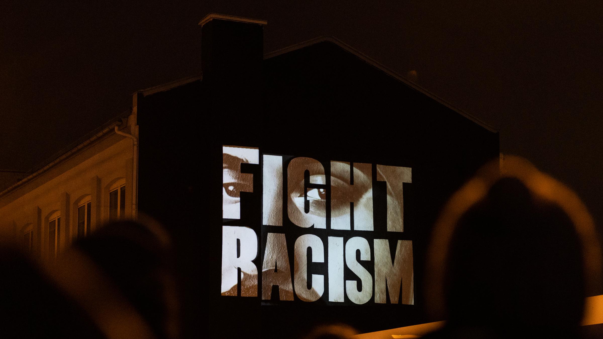 "Fight Racism" mit den Gesichtern der Opfer steht auf einer Hausfassade an der Camberger Brücke zum Gedenken an die Opfer der rassistisch motivierten Anschläge von Hanau im Jahr 2020. Das Künstlerkollektiv âKollektiv ohne Namenâ fürhte die Aktion durch.