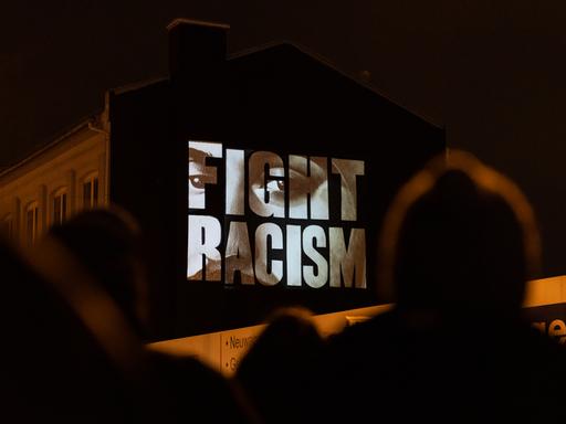 "Fight Racism" mit den Gesichtern der Opfer steht auf einer Hausfassade an der Camberger Brücke zum Gedenken an die Opfer der rassistisch motivierten Anschläge von Hanau im Jahr 2020. Das Künstlerkollektiv âKollektiv ohne Namenâ fürhte die Aktion durch.