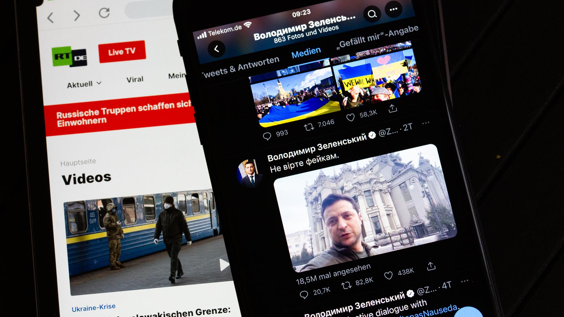 Auf dem Bildschirm eines Tablets (l) ist die Website des russischen Fernsehsenders RT zu sehen. Rechts ist auf dem Bildschirm eines Smartphones der offizieller Twitter-Account des ukrainischen Präsidenten Selenskyj zu sehen. 