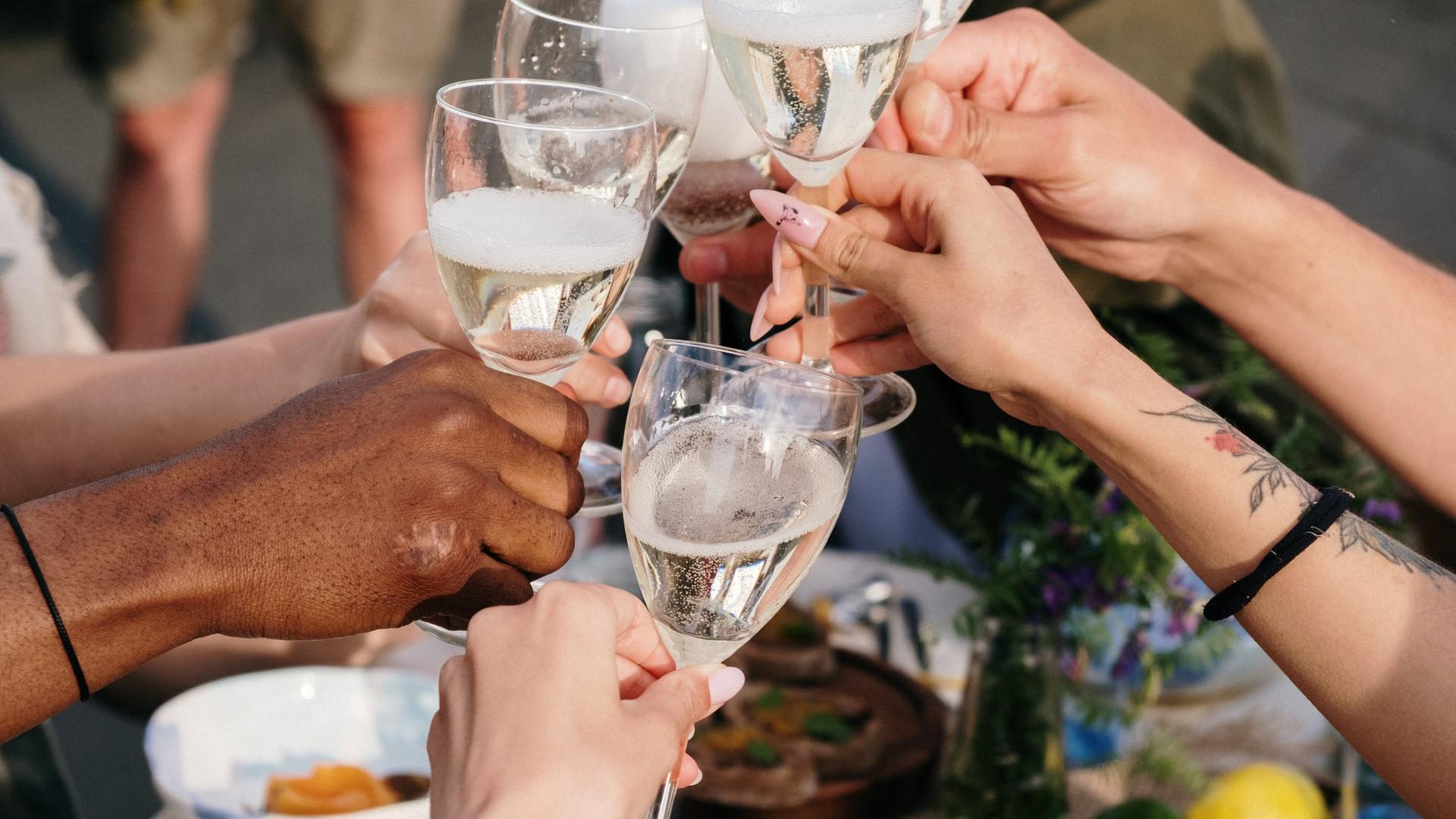 Mehrere Hände stoßen mit Wein-Gläsern in der Hand an. Mehrere Hände stoßen mit Wein-Gläsern in der Hand an.