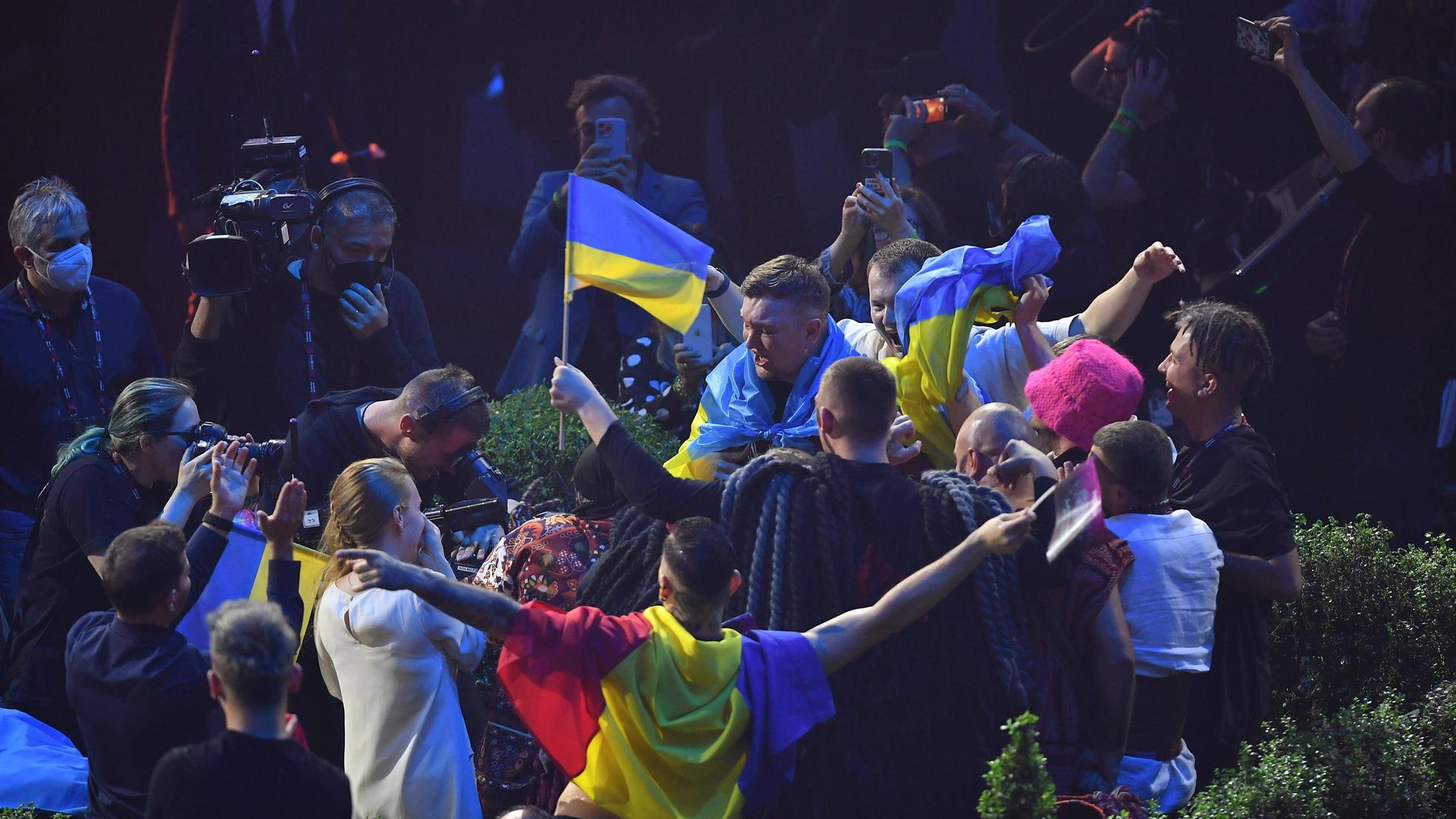Die Band Kalush Orchestra aus der Ukraine feiert nach dem Sieg beim Eurovision Song Contest 2022. Ukrainische Fahnen werden geschwenkt, es wird gefilmt und fotografiert.  