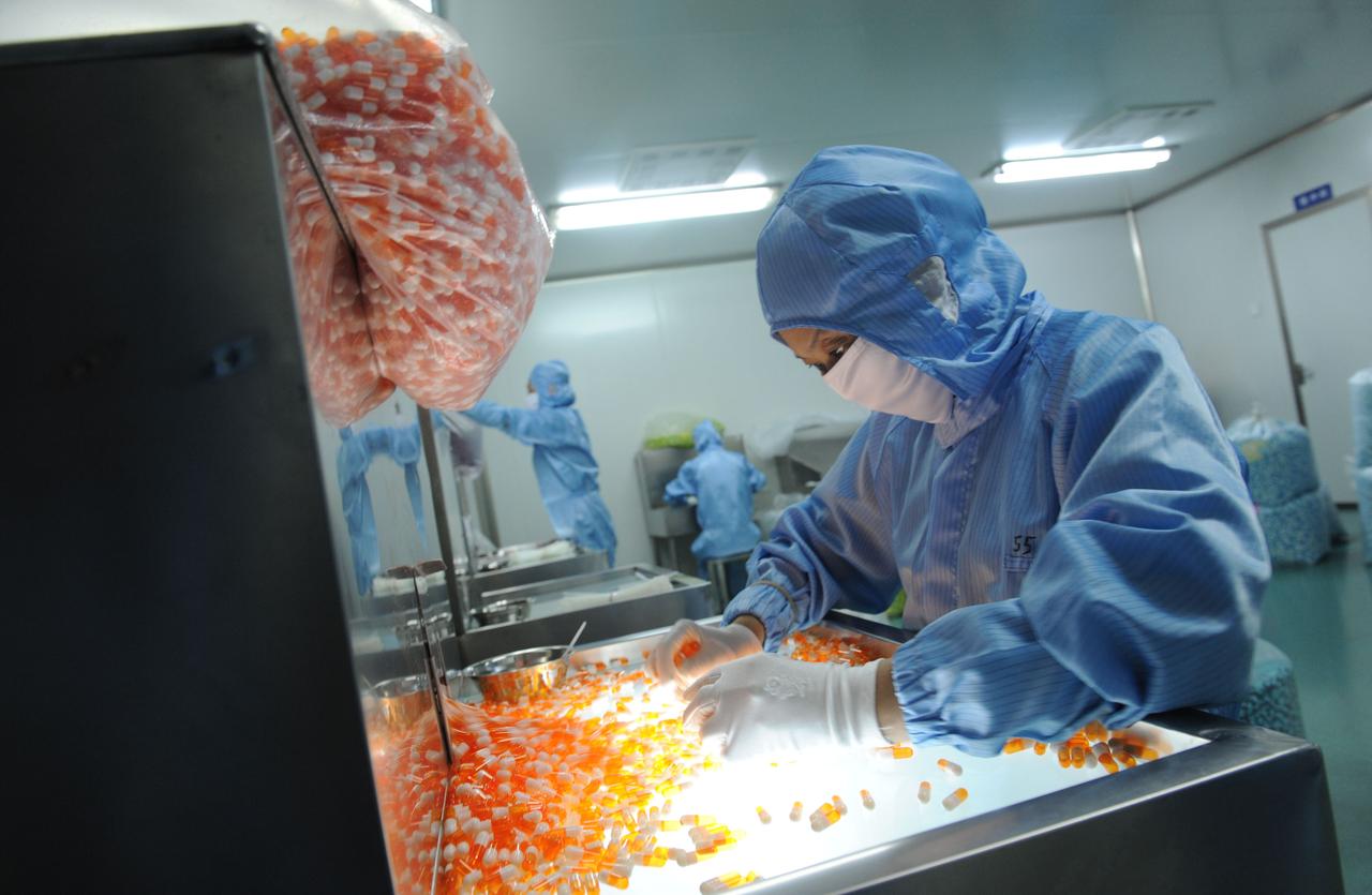 Eine Frau arbeitet in Schutzkleidung in einer Pharmafabrik in Xinchang, China. Eine Frau arbeitet in Schutzkleidung in einer Pharmafabrik in Xinchang, China.