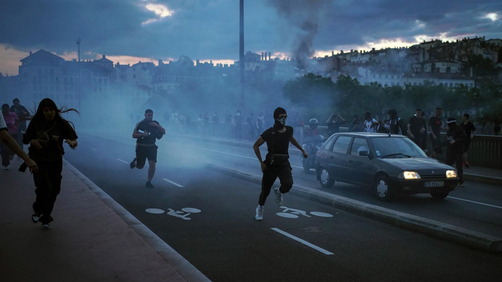 Frankreich, Lyon: Menschen fliehen während es zu Zusammenstößen mit der Polizei kommt.