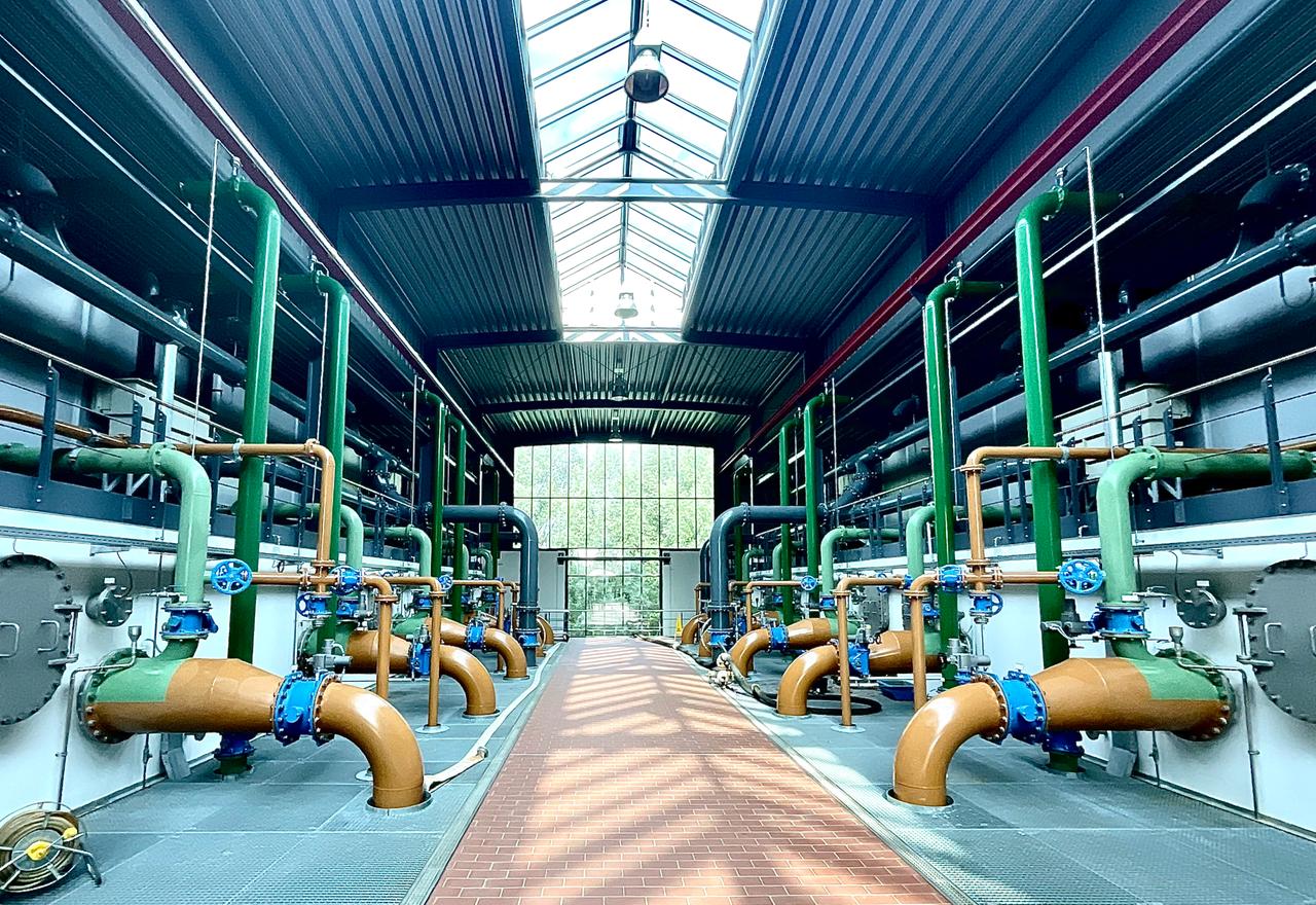 Blick in eine Halle mit braunen und grünen Leitungen und Rohren Blick in eine Halle mit braunen und grünen Leitungen und Rohren