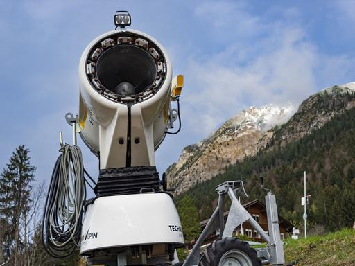 Eine Schnee-Schnellkanone steht vor einem Bergpanorama in Bayern