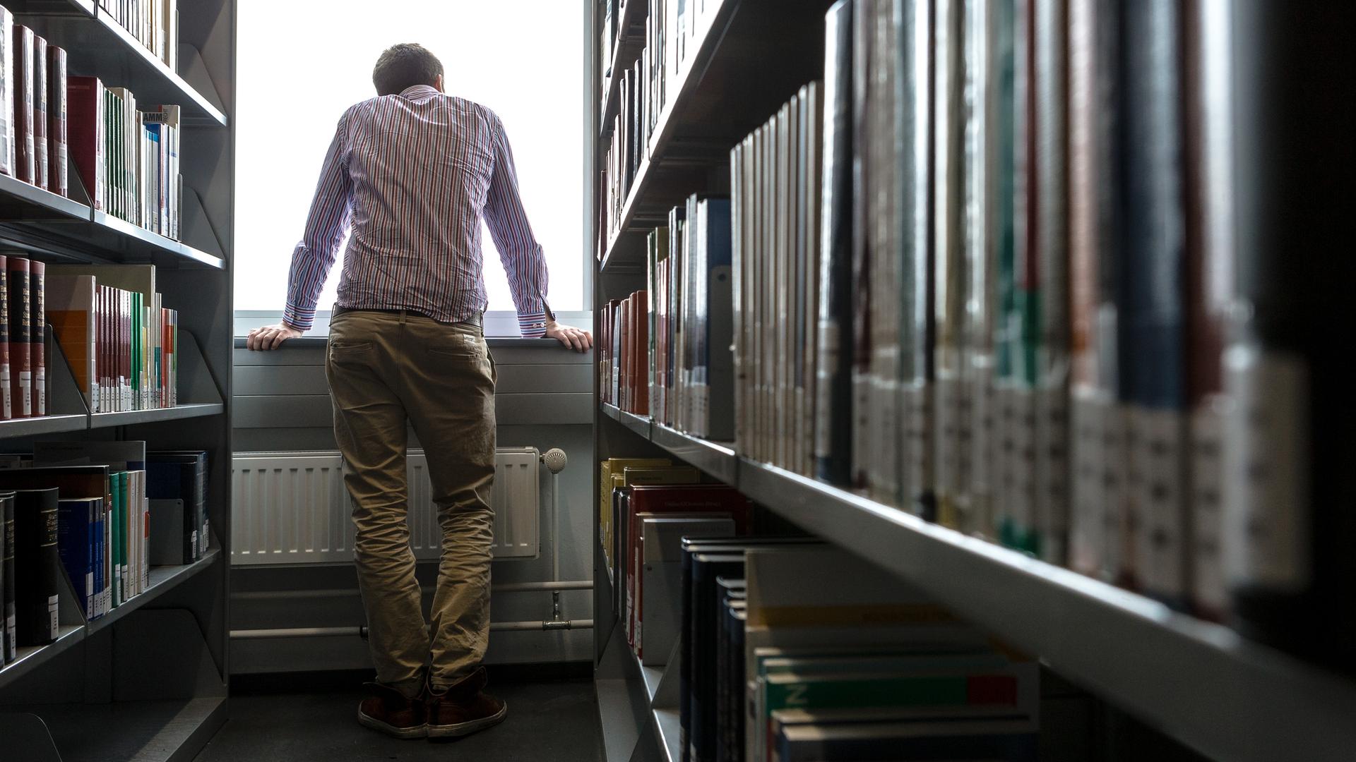 Ein Student blickt in einer Hamburger Universitätsbibliothek aus dem Fenster.