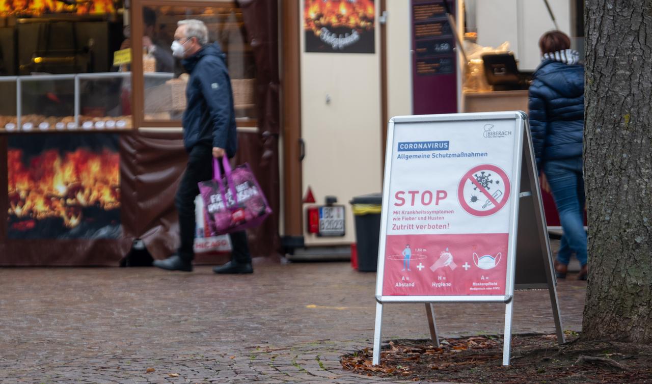 Am Markt in Biberach weist ein Schild auf die Corona-Verhaltensregeln hin. Im Hintergrund ist ein Mann mit Mund-Nase-Schutz zu sehen, der eine Einkaufstasche trägt. Am Markt in Biberach weist ein Schild auf die Corona-Verhaltensregeln hin. Im Hintergrund ist ein Mann mit Mund-Nase-Schutz zu sehen, der eine Einkaufstasche trägt.