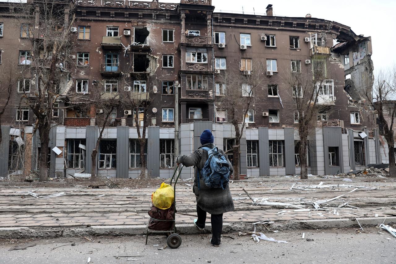 Eine Frau steht vor einem zerstörten Wohnhaus in der ukrainischen Hafenstadt Mariupol. Eine Frau steht vor einem zerstörten Wohnhaus in der ukrainischen Hafenstadt Mariupol.