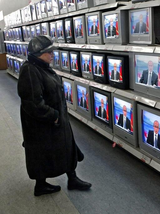 Eine Frau verfolgt in der Fernsehabteilung eines Kaufhauses in Moskau die jährlichen Live-Fragestunde an Präsident Putin im russischen Fernsehen (2003).