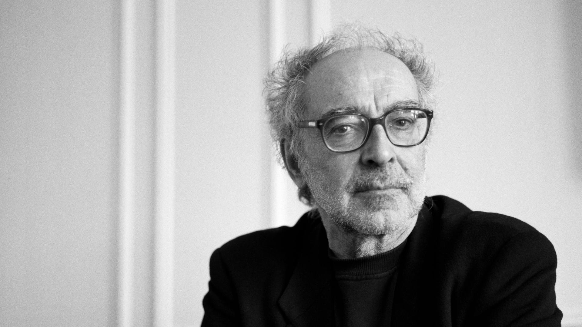 Schwarz-weiß Porträt von Jean-Luc Godard im April 2001. Mit gefalteten Händen schaut er konzentriert Richtung Kamera. Schwarz-weiß Porträt von Jean-Luc Godard im April 2001. Mit gefalteten Händen schaut er konzentriert Richtung Kamera.