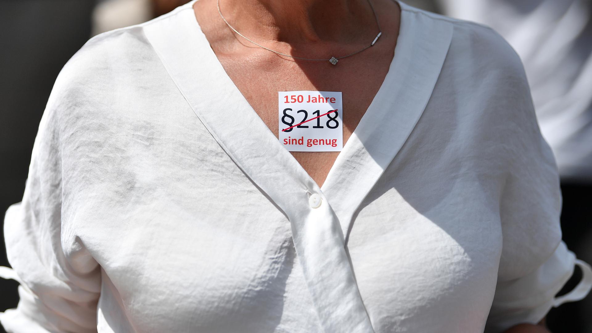 "§218. 150 Jahre sind genug" steht auf dem Sticker einer Demonstrantin, der auf ihrem Dekolleté klebt.