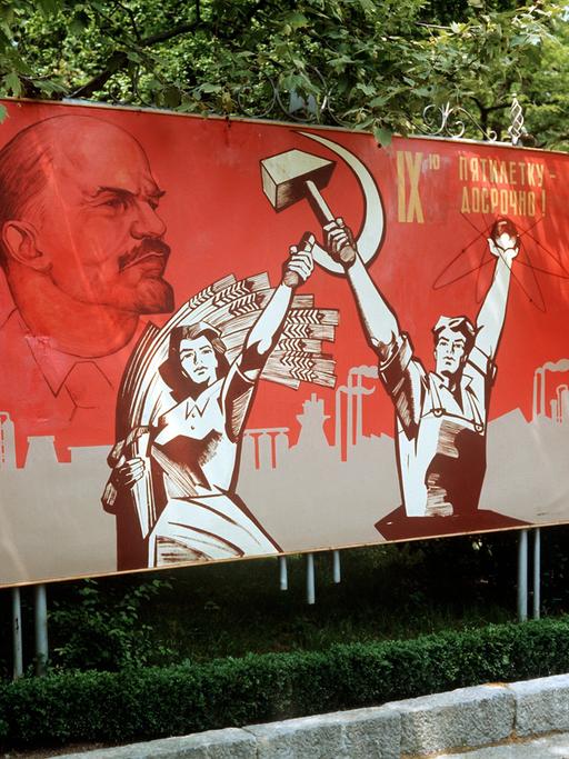 Ein großformatiges Plakat mit Lenin-Konterfei und der Darstellung von Arbeiter und Bäuerin mit Hammer und Sichel