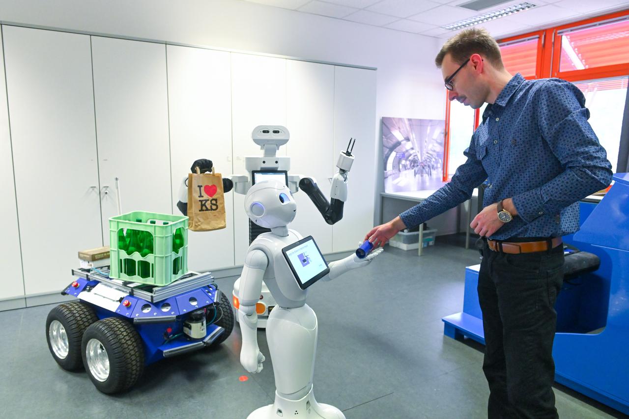 Jemand drückt Roboter Pepper ein kleines Objekt in die Hand. Jemand drückt Roboter Pepper ein kleines Objekt in die Hand.