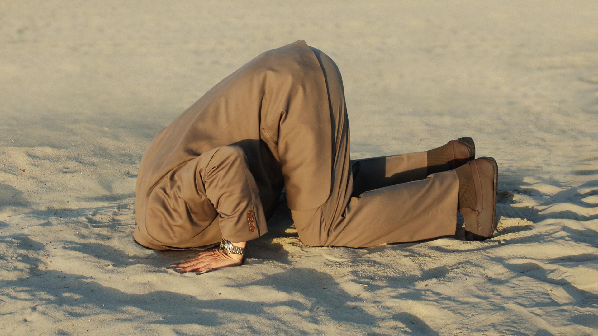 Geschäftsmann steckt seinen Kopf in Sand am Strand. Geschäftsmann steckt seinen Kopf in Sand am Strand.