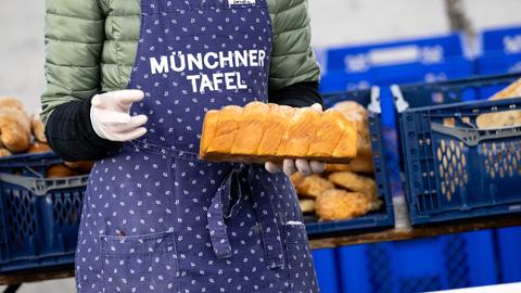 Eine Frau hält bei der Münchner Tafel ein Brot in der Hand 