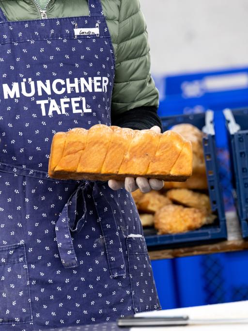Eine Frau hält bei der Münchner Tafel ein Brot in der Hand 