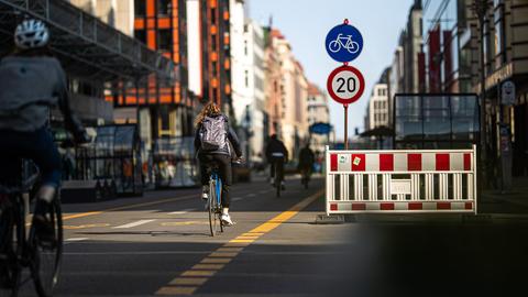 Fahrradfahrer in der Berliner Friedrichstraße und ein Schild, das eine Geschwindigkeitsbegrenzung auf 20 Stundenkilometer anzeigt.
