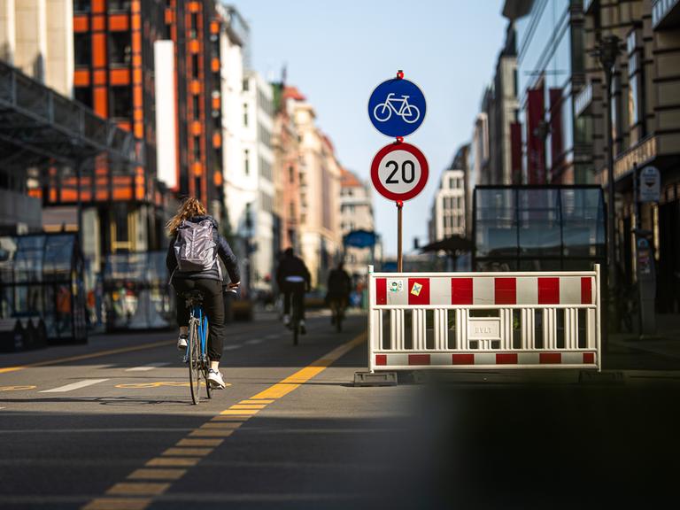 Fahrradfahrer in der Berliner Friedrichstraße und ein Schild, das eine Geschwindigkeitsbegrenzung auf 20 Stundenkilometer anzeigt. 
