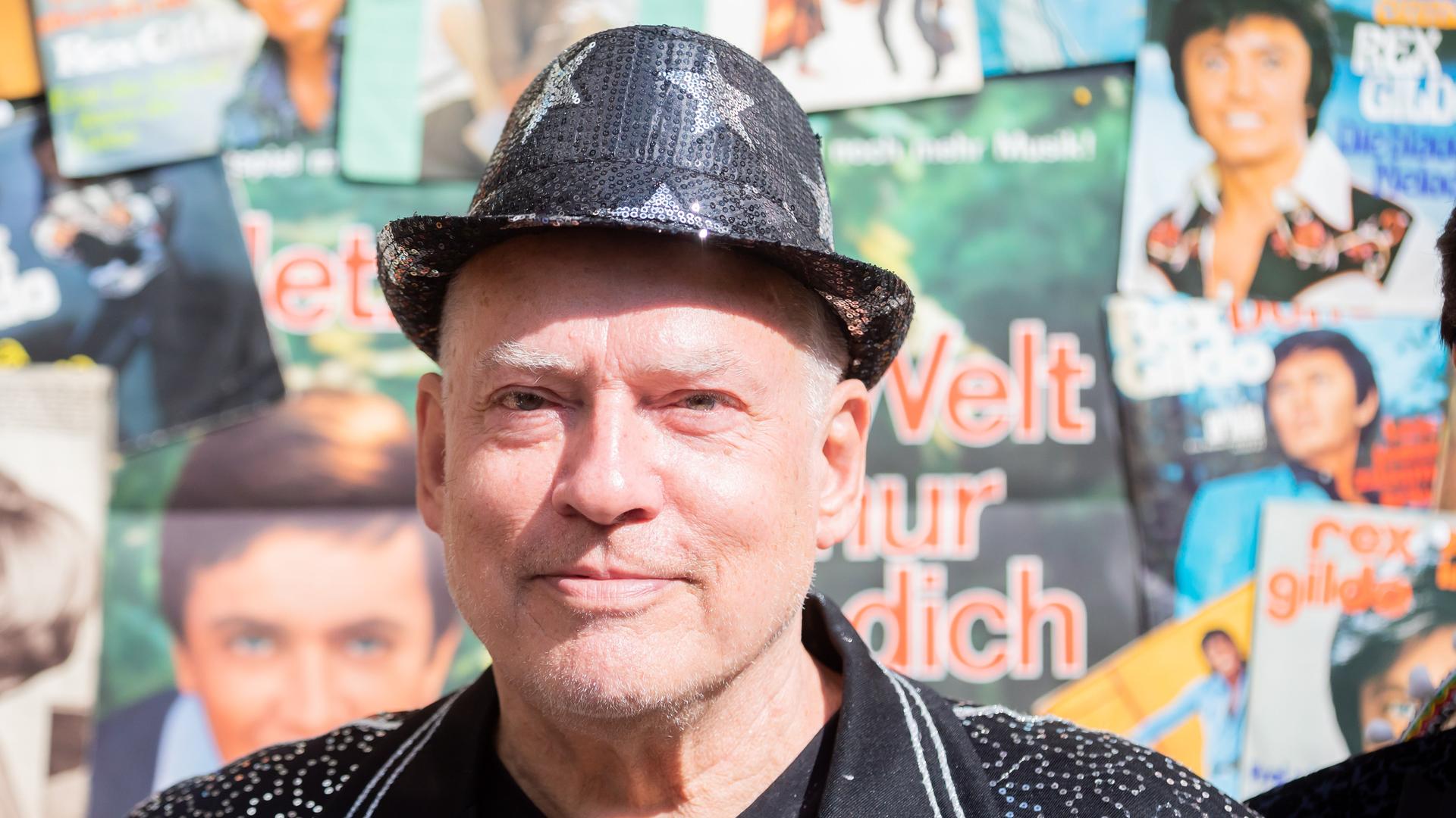 Rosa von Praunheim steht bei einem Pressetermin vor einer Wand voller Ausschnitte der Musik- und Klatschpresse. Rosa von Praunheim steht bei einem Pressetermin vor einer Wand voller Ausschnitte der Musik- und Klatschpresse.