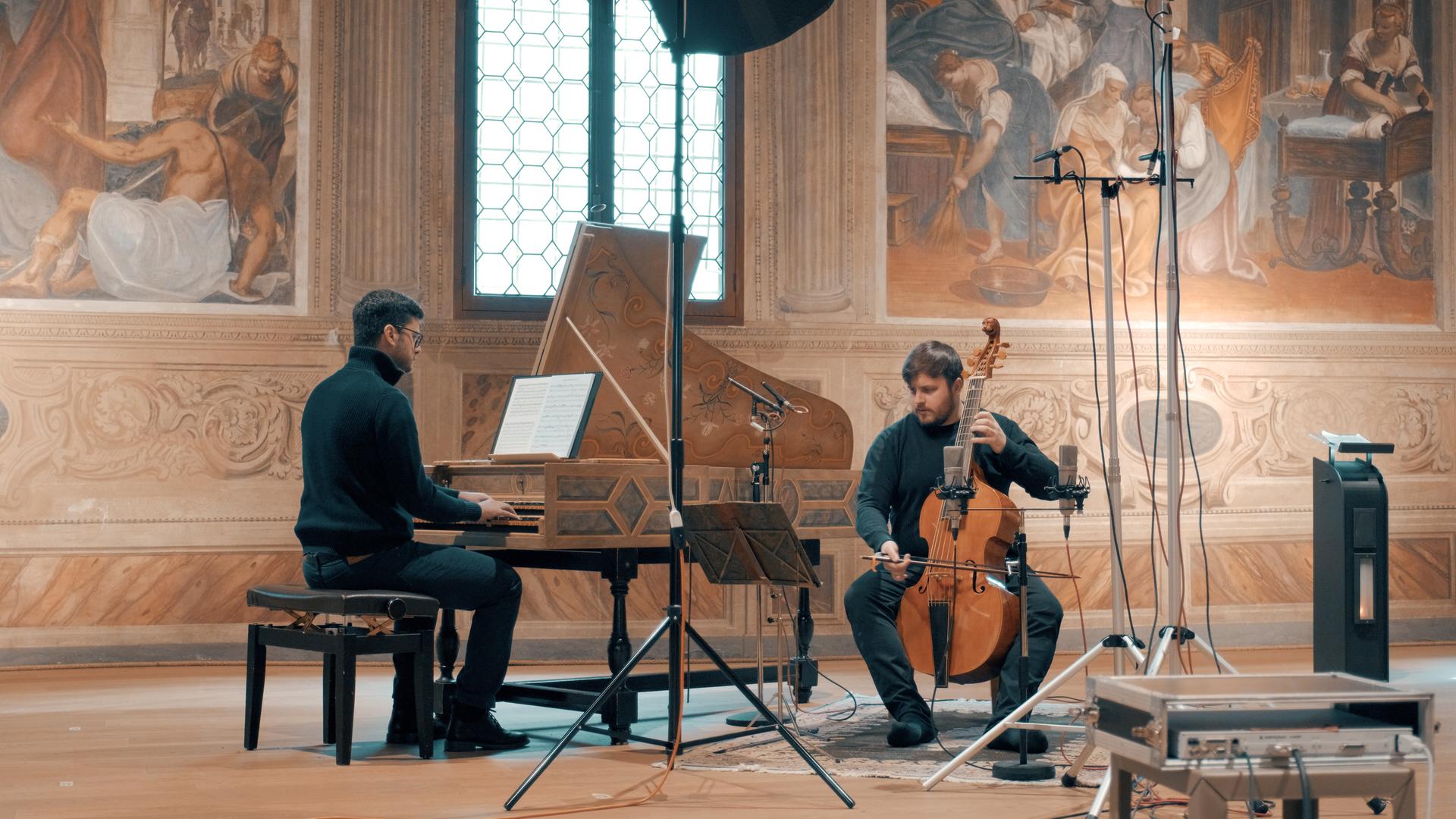 Ein Mann sitzt an einem Cembalo, rechts von ihm sitzt ein Mann auf einem Stuhl und hält vor sich eine Viola da Gamba. Sie sind umgeben von Mikrofonen und Kabeln. Ein Mann sitzt an einem Cembalo, rechts von ihm sitzt ein Mann auf einem Stuhl und hält vor sich eine Viola da Gamba. Sie sind umgeben von Mikrofonen und Kabeln.