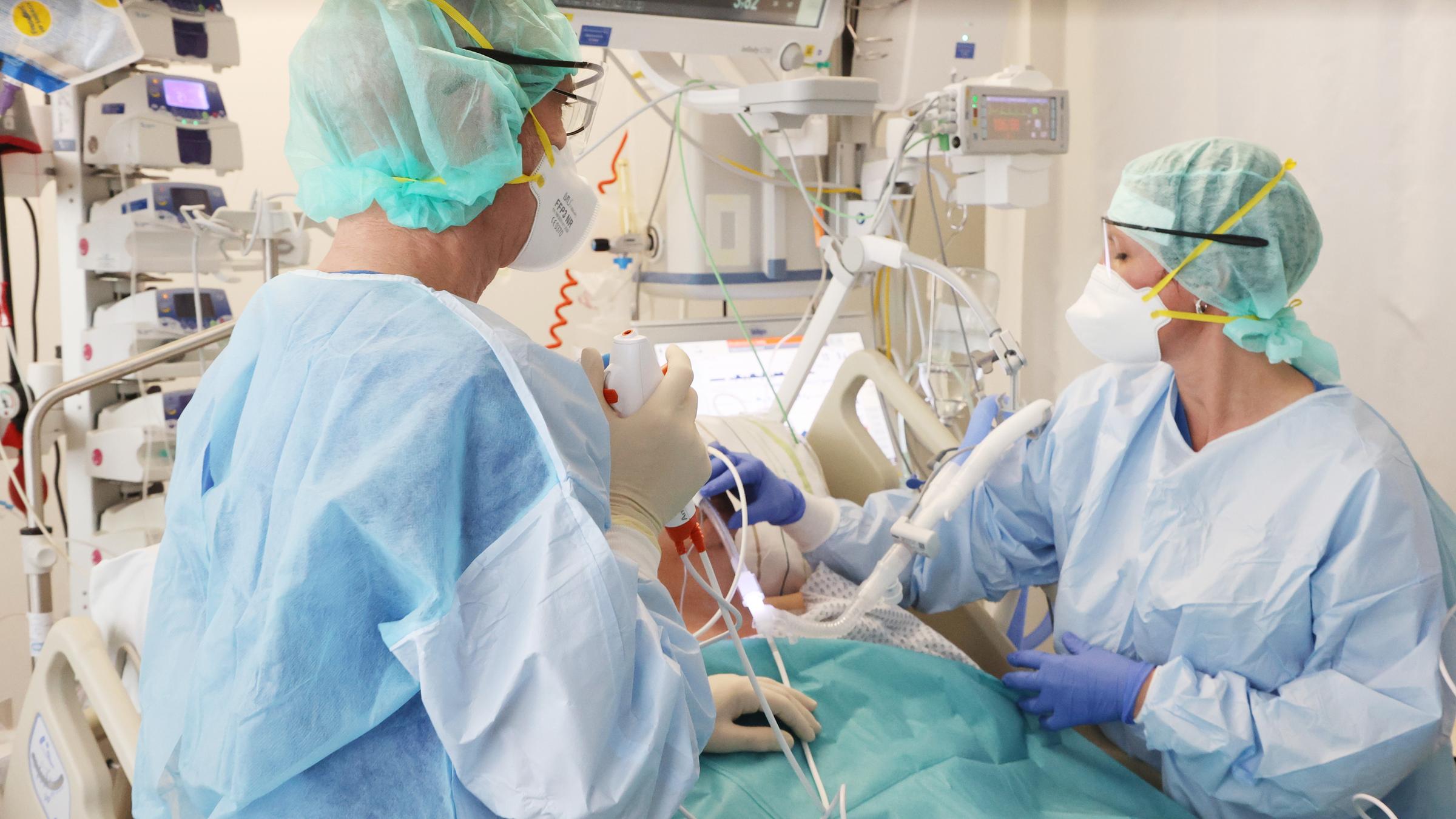Ãrzte und Pfleger untersuchen einen Patienten auf einer Covid-19-Intensivstation.