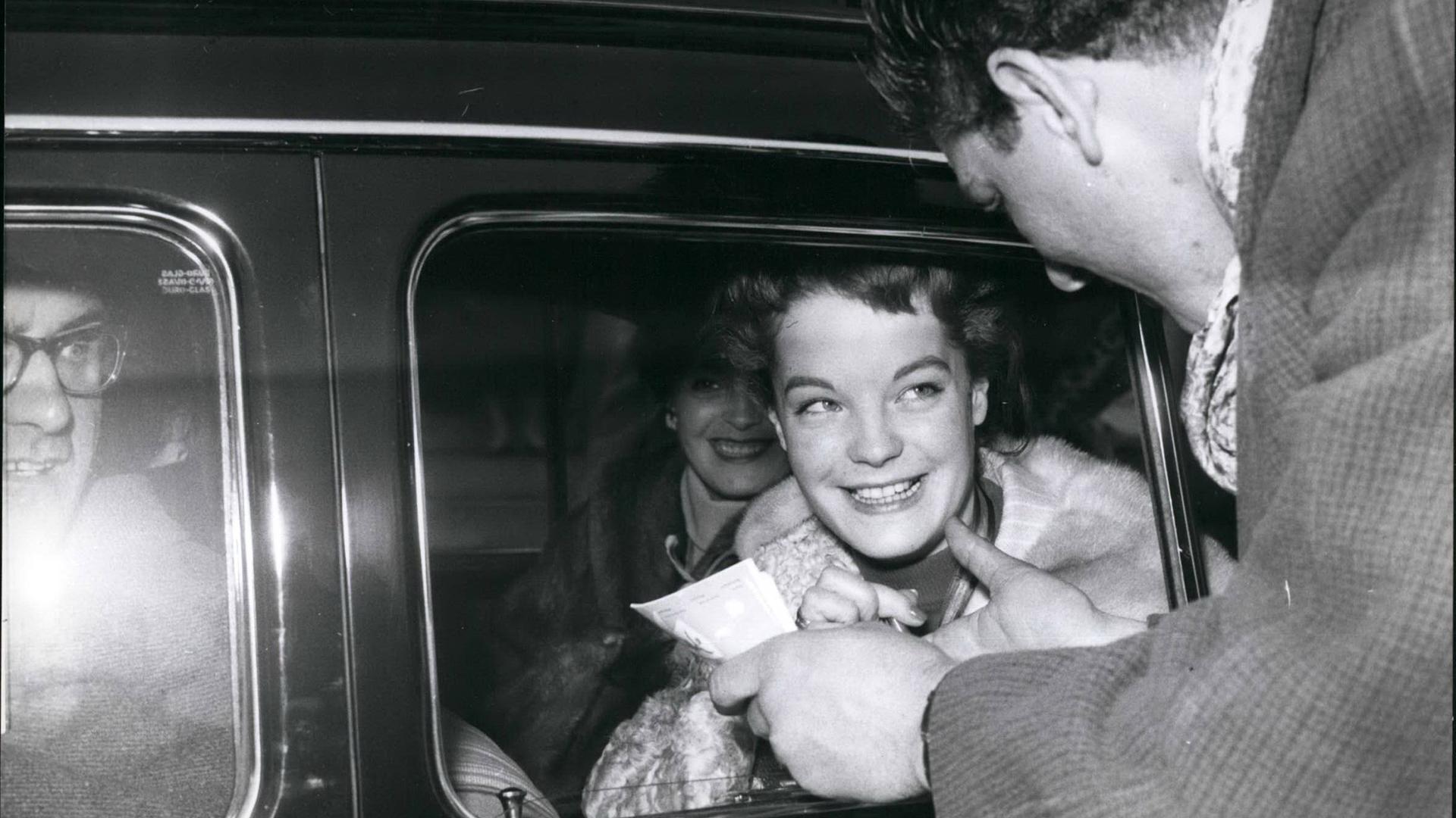 Romy Schneider. Eine junge Frau sitzt in einem Auto und wird noch einem Mann angesprochen. Romy Schneider. Eine junge Frau sitzt in einem Auto und wird noch einem Mann angesprochen.