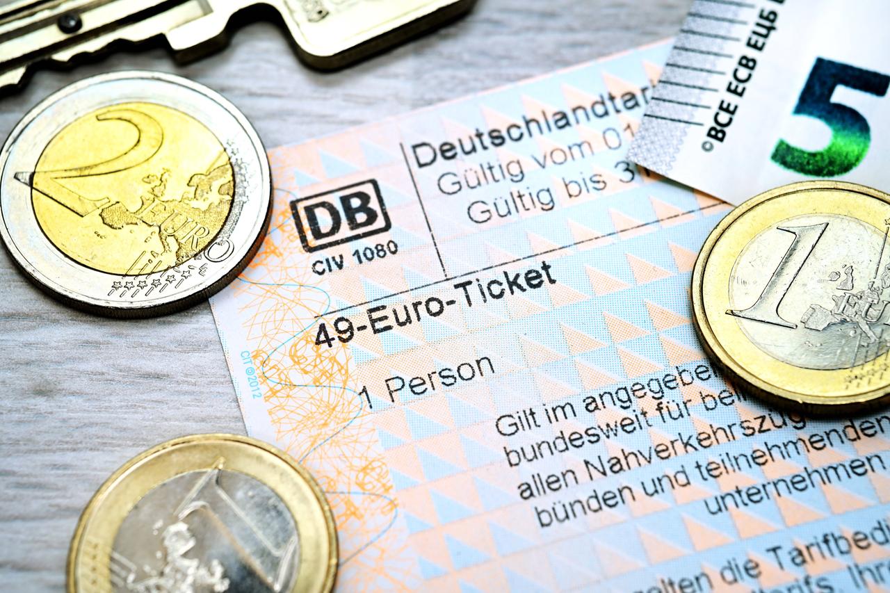 Fahrschein mit Aufschrift 49-Euro-Ticket und Euromünzen Fahrschein mit Aufschrift 49-Euro-Ticket und Euromünzen
