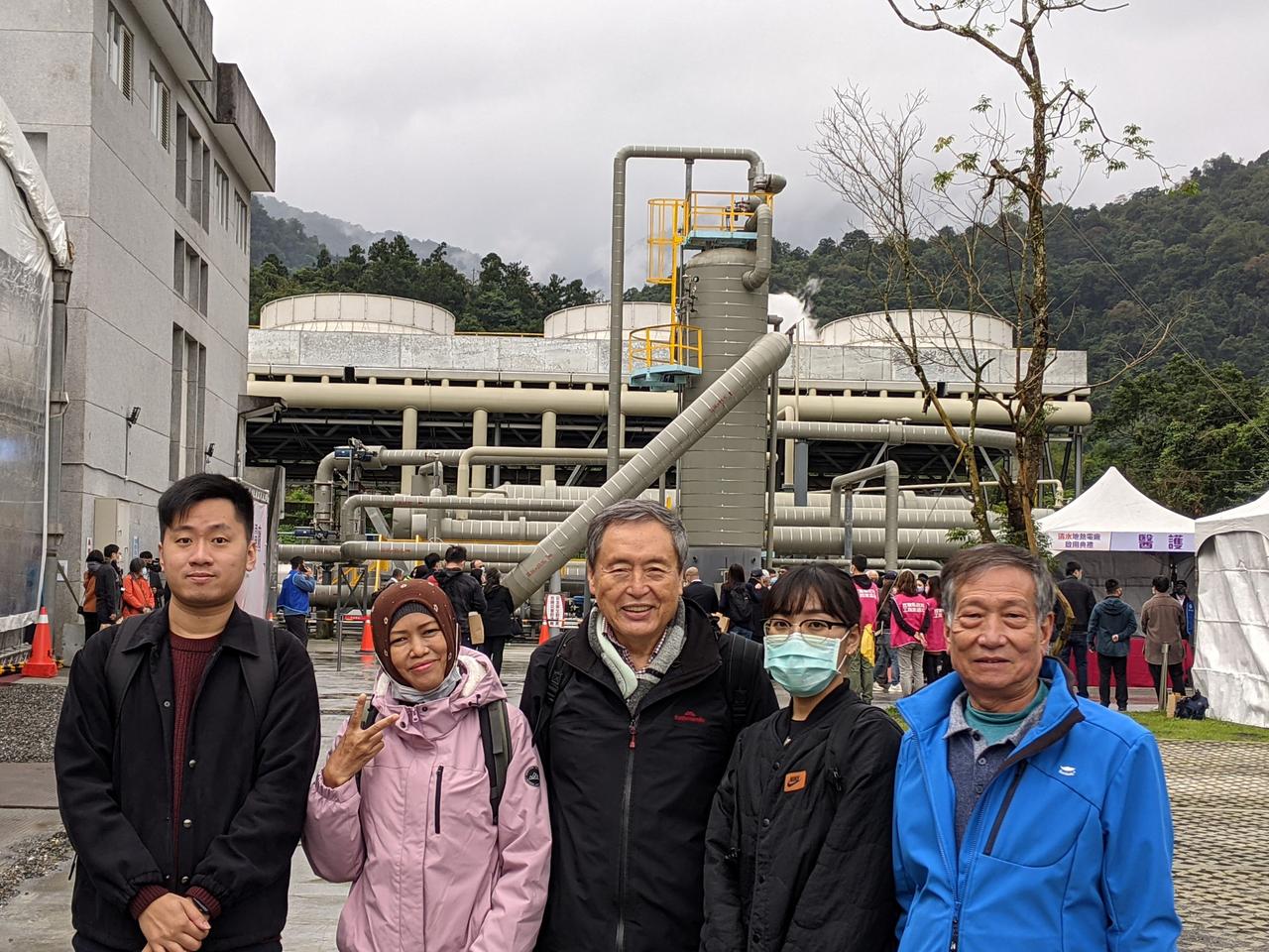 Eine Gruppe Menschen posiert für ein Foto vor einem Erdwärmekraftwerk.
