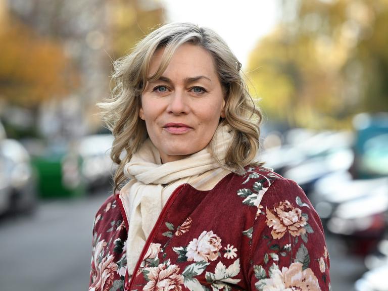Die Schauspielerin Gesine Cukrowski steht auf einer Straße. 