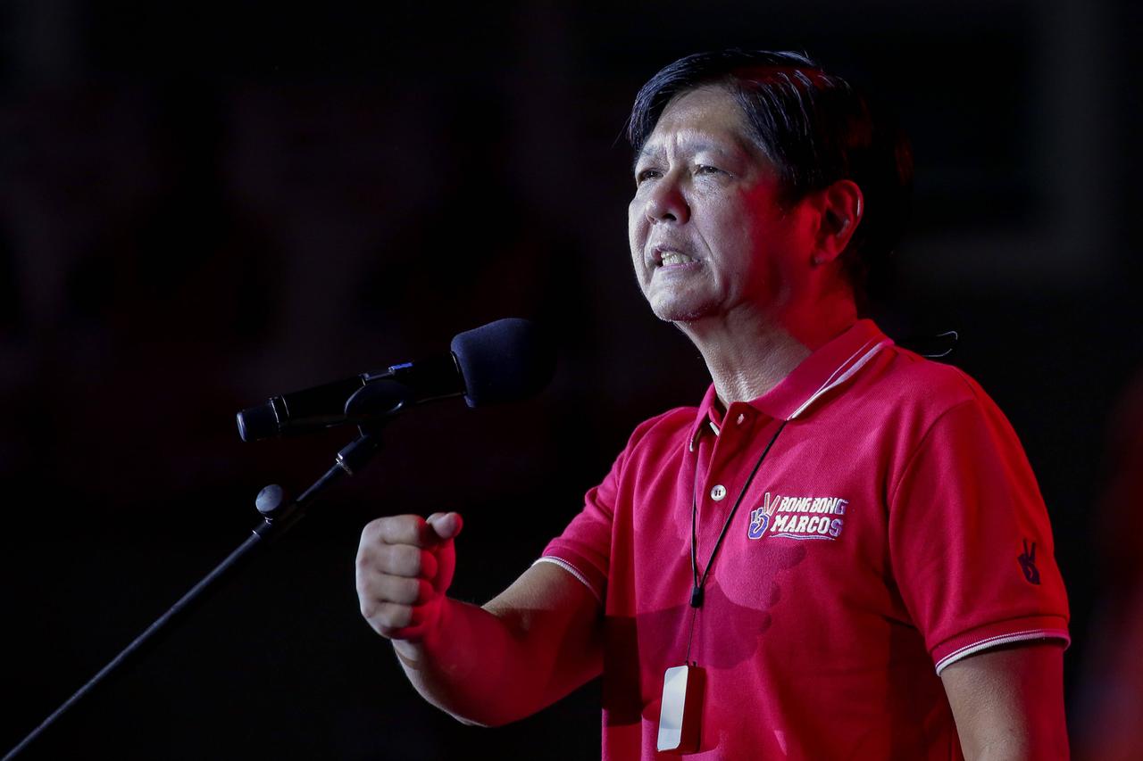 Ein Mann in rotem Shirt spricht mit geballter rechter Faust emotional in ein Mikrofon.