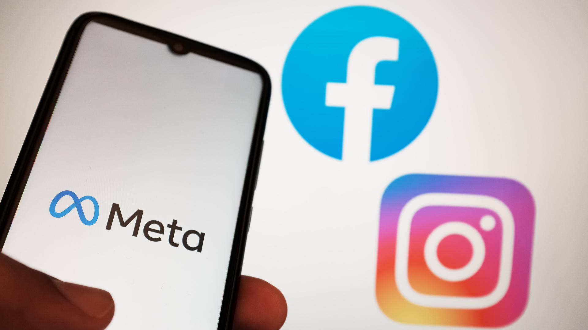 Auf dem Foto sieht man eine Hand. Sie hält ein Handy. Auf dem Bild-Schirm sieht man das Logo von der Firma Meta. Daneben sieht man die Logos von Instagram und Facebook. Auf dem Foto sieht man eine Hand. Sie hält ein Handy. Auf dem Bild-Schirm sieht man das Logo von der Firma Meta. Daneben sieht man die Logos von Instagram und Facebook.
