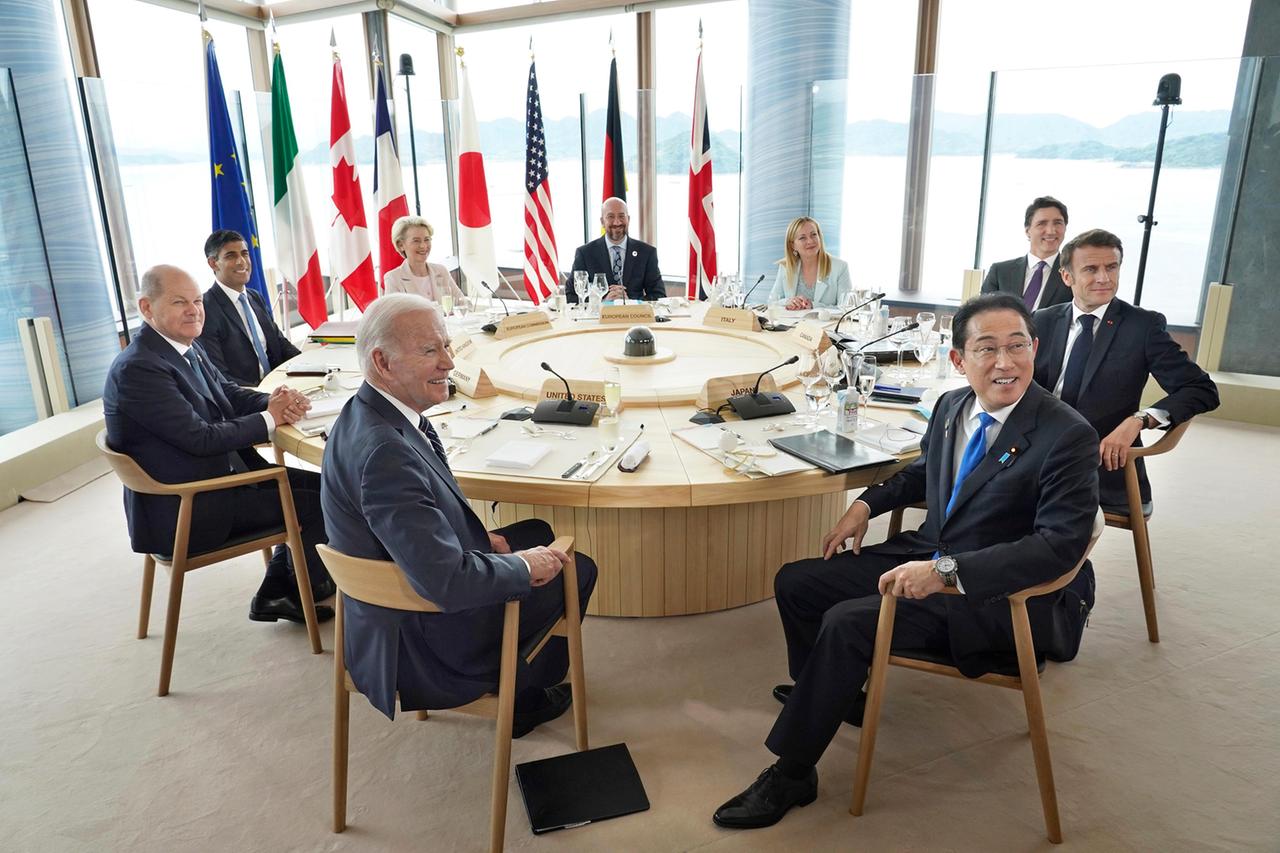 Die Staats- und Regierungschefs der G7-Staaten sitzen um einen runden Tisch. Hinter ihnen die Landesfahnen.