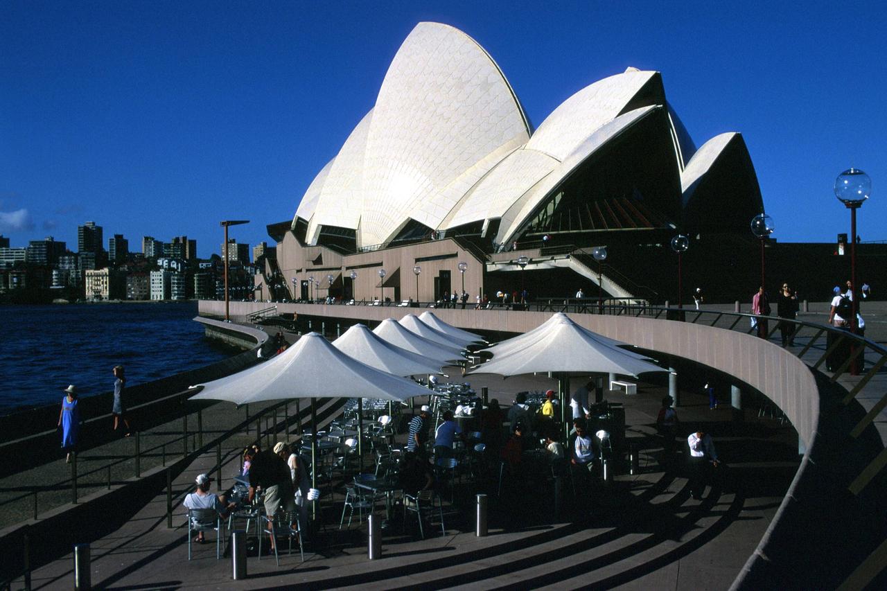Gute Aussichten in Sydney nach dem harten Lockdown - vor dem spekaktulären Opernhaus sitzen Gäste in einem Café auf der Terrasse.
