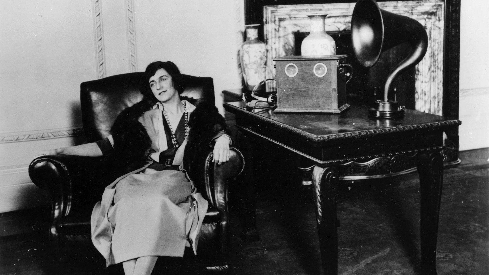 Eine Frau sitzt 1922 in einem Sessel und hört Radio. Eine Frau sitzt 1922 in einem Sessel und hört Radio.