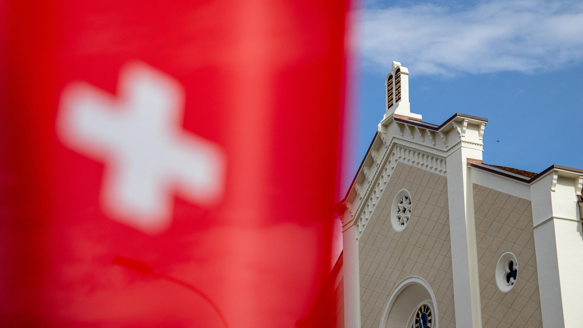 Im Hintergrund eine Synagoge, im Vordergrund die Schweizer Flagge. Im Hintergrund eine Synagoge, im Vordergrund die Schweizer Flagge.