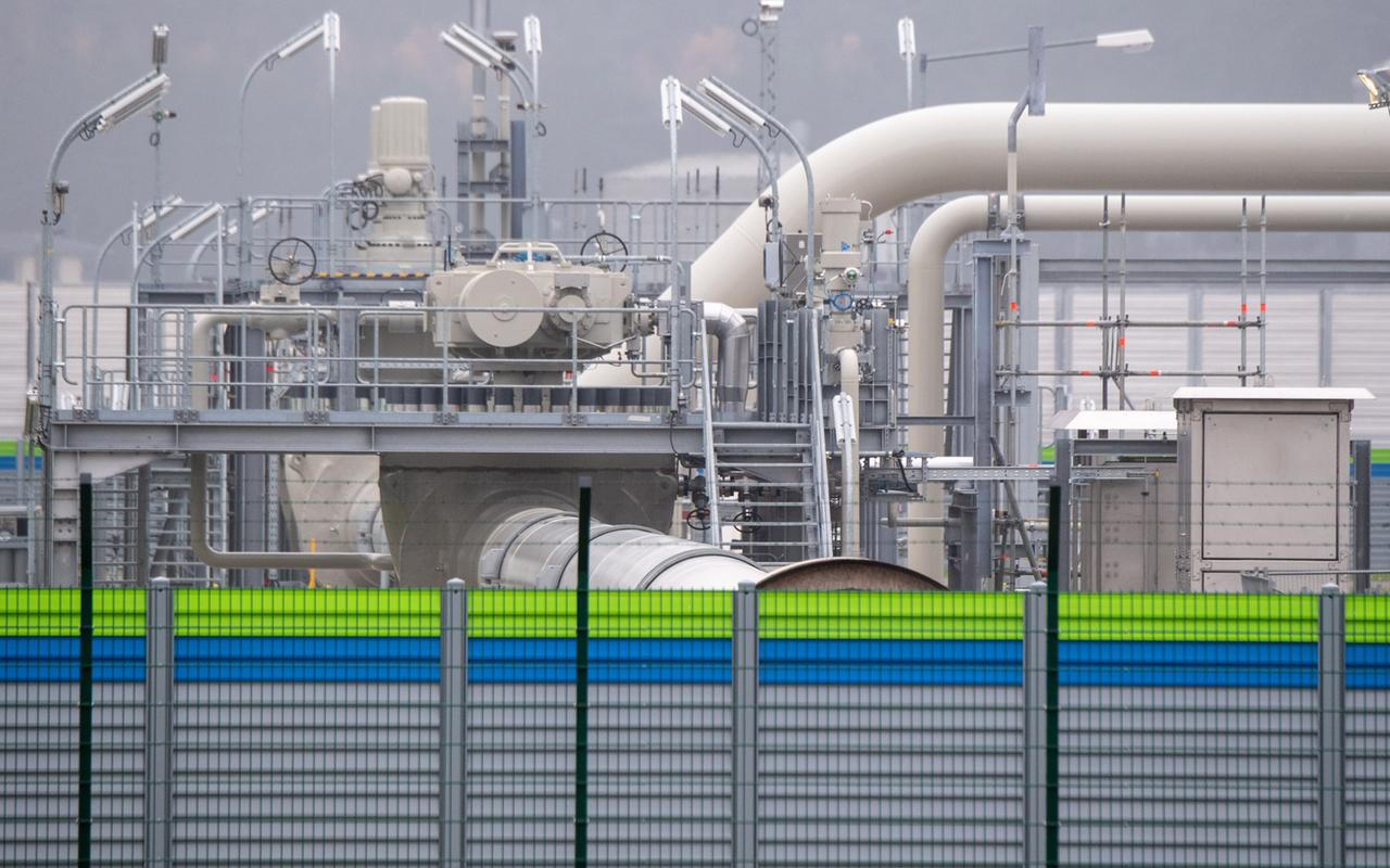 Das Foto zeigt einen Absperrzaun mit grünen und blauen Streifen am oberern Ende. Dahinter ist ein Teil der Gasempfangsstation der Ostseepipeline Nord Stream 2 zu sehen, durch die der Gazprom-Konzern Deutschland mit Gas beliefern will.