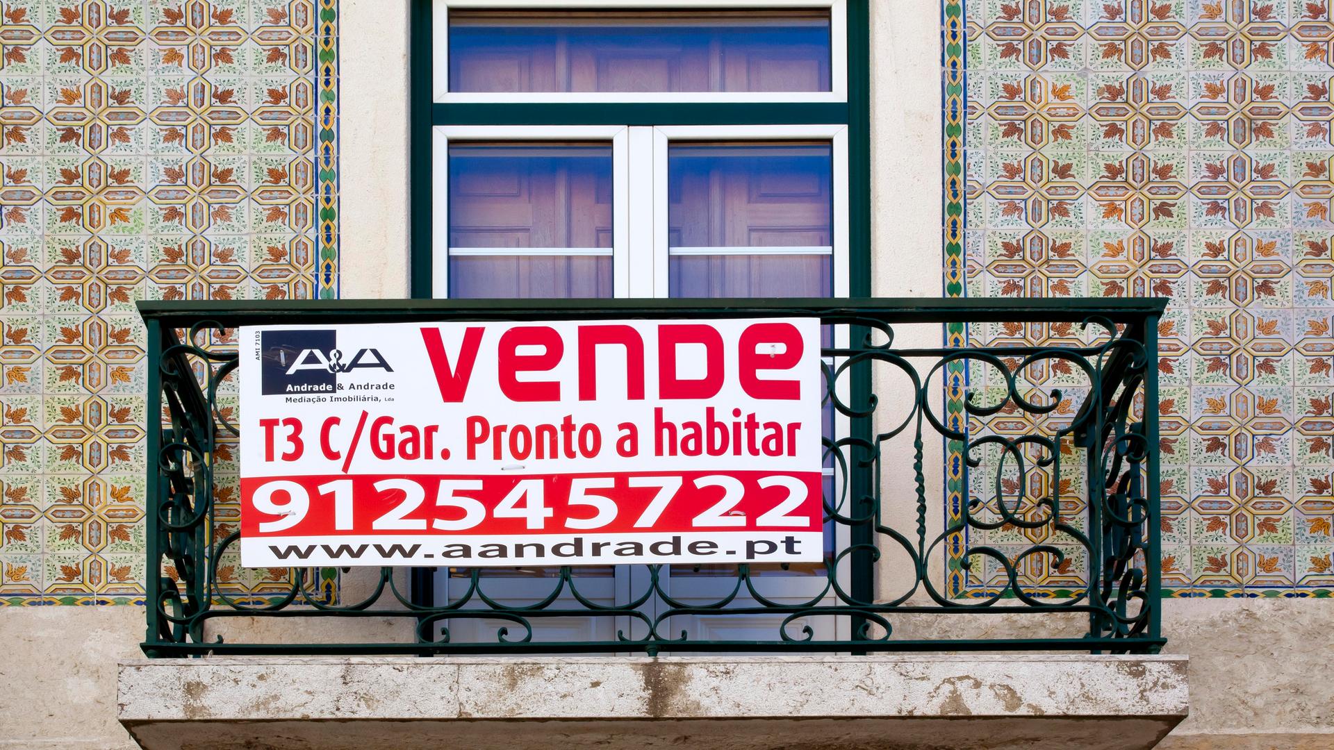 Ein Schild hängt an einem Balkon in Lissabon und macht auf den Immobilienverkauf aufmerksam.